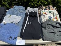 Overview of assorted men's casual clothing items laid out on a table including jeans, sweatpants, t-shirts, and shirts.