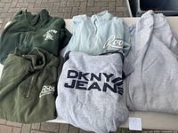 Six men's tops, including fleece jackets and sweatshirts in green, gray and blue-gray. Visible branding includes 'Roots Sporting' and 'DKNY Jeans'.