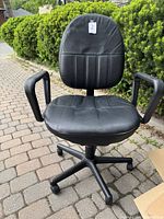 Front view of the black leather office swivel chair showing armrests, padded seat and backrest, five-star base with wheels.