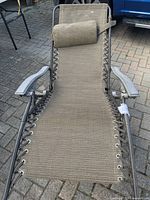 Full view of the tan chaise lounge chair showing fabric and pillow on metal frame.