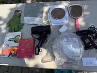 Top-down view of all health supplies including muscle support glove, heat pack, hair dryer, two mirrors, insect zapper racket, and medication boxes.