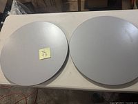 Two light gray round Ikea Lazy Susan turntables placed side by side on a white surface.