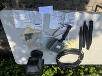 A table with outdoor lighting system components including wiring, lighting fixture, plastic stakes, and instruction manuals.