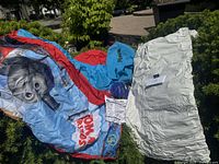 Inflatable bed partially unfolded outdoors, showing Thomas the Train cartoon artwork, carrying bag, and white inflatable mattress section.
