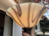 Close-up of the cream-colored glass lamp shade with brown swirling lines, ornate metal pole visible at base of shade.