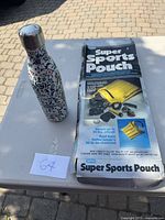 Photo showing the decorative water bottle and the Super Sports Pouch original packaging on a white surface outdoors.