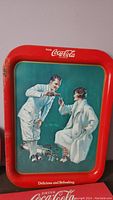 Coca-Cola calendar with red frame featuring a man and woman toasting with Coca-Cola glasses and slogans.