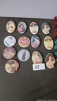 Oval Coca-Cola pocket mirrors arranged in two rows showing various vintage advertising images mainly of women and classic Coke logos