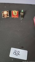 Three Coca-Cola pins on display: vintage clock design, woman with Coca-Cola, and classic bottle.