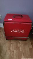 Front view of the red metal cooler showing Coca-Cola logo and handle on top.