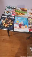 Cookbooks arranged on a table showing vegan and self-care recipe titles with colorful food covers.