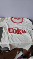 White shirt with red ringer collar, front text 'Enjoy Coke' in red