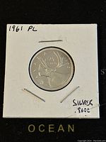Obverse side of the 1961 Canadian 25 cent silver coin showing the caribou design with text indicating the silver content and condition (PL).