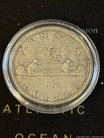 Front side of 1963 Canadian silver dollar coin showing canoe and paddlers design with year and denomination.