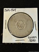 Image of the reverse side of the 1964 Canadian silver dollar showing floral emblem and inscriptions indicating half a century (1864-1964) and silver content (.8000).