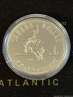 Reverse side of the coin featuring cowboy on bucking horse and Calgary skyline with commemorative dates 1875-1975.