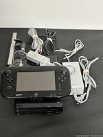 Wii U console, GamePad, sensor bar, power cords all laid out on surface
