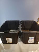 Two large black plastic storage bins without lids, side by side, showing exterior and interior surfaces.