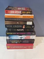 Stack of 11 assorted books showing titles and authors clearly except for a few partially obscured.