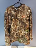 Front view of Realtree camo hoodie with hood and orange logo on chest.