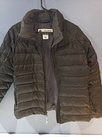 Full view of black Columbia puff jacket with zipper open showing inner lining and size label.