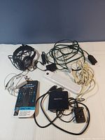 Full overview photo of the electronic accessories lot including headphones, power strip, various cables and adapters