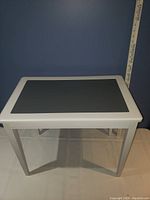 Full view of rectangular end table showing white frame and black inset top.