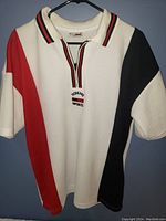 Front view of Tommy Sports golf shirt with white, red, and black color blocks and zipper collar detail.