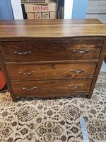Front view of the wooden dresser showing three drawers with metal handles and wood grain finish