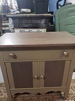 Front view of the refinished wash stand cabinet showing drawer and two doors with knobs.