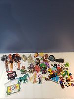 Full view of the toy collection showing variety of toy figurines, toys, and game pieces against a white background.