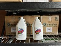 Shelf with two 1 gallon bottles of Benefect Botanical Quantum Cleaner and cardboard boxes labeled Benefect behind them.