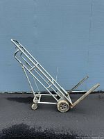 Side view of the gray metal 4 wheel platform cart with inclined hand truck configuration, showing two large rear wheels and two small caster wheels.