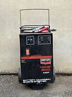 Front view of the Century battery charger and engine starter unit, showing model details, control knobs, and attached cables.