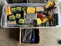 Photo showing the full kit contents in a plastic bin including multiple Scotch-Brite pads, various sponges, hand frames, brushes, and cleaning accessories.