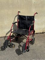 Side and front views of the used Medline Ultralight Transport Wheelchair against a wall showing overall condition and features.