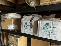 Boxes of Abatix coveralls size XL on shelf, partially open box showing packaging.