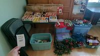 Wide view of the lot showing Christmas decorations in storage bins and boxes along with folding table and chairs.
