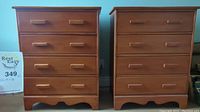 Two wooden dressers with a warm finish, each with rectangular handles and curved cutout base design