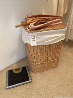Wicker laundry hamper with white fabric liner showing wear, digital scale on floor in front