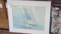Framed watercolor artwork by Tyrus Wong, hanging indoors with visible white picket fence and figure under rainy sky.
