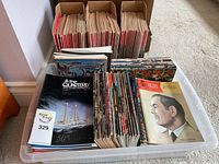 Wide view of the magazines and related publications stored in plastic bin and cardboard holders.