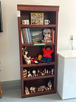 Front view of wooden bookshelf filled with various items, showing structure and size