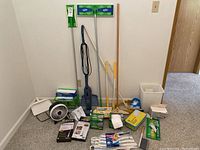 Photo of the full lot including Bissell Magic Vac vacuum cleaner, mop handles, mop refills, fan, dustpan, cleaning pads, manuals, and trash bin.