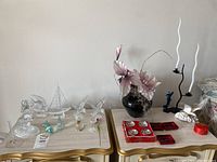 Full view showing assorted crystal and glass figurines including dolphin, sailboat, and birds, alongside Asian style bowls and black metal candlestick.