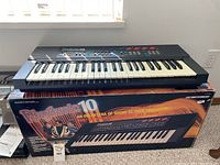 Rhythmic 10 keyboard placed on top of its original box showing front view and box graphics.