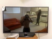 Front view of the LG 42-inch TV on wooden stand with manual in plastic bag and sticker label.