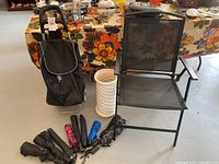 Rolling cart with fabric bag, white umbrella stand, black folding chair, and five small umbrellas arranged on the floor.