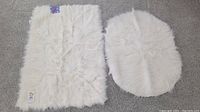 Photo of two white faux fur scatter rugs, one rectangular and one oval-shaped, laid flat showing texture and size comparison.