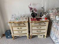 Pair of cream and gold vintage style side tables with various decorative items on top